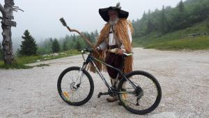 a man in a costume standing next to a bike at Chalet Zlatica Velika Planina in Stahovica