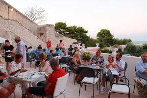 a group of people sitting at tables on a patio at Hotel Boutique Il Castellino Relais in Vieste