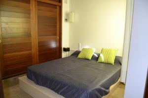 a bedroom with a bed with two green pillows at Casa Fayas in Ciutadella