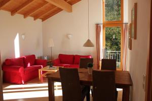 ein Wohnzimmer mit einem Tisch und einem roten Sofa in der Unterkunft Ferienwohnungen Almrausch in Oberammergau