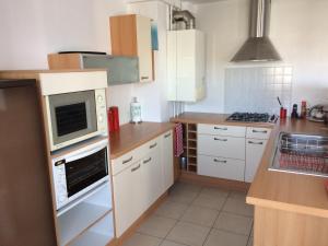 a kitchen with white cabinets and a microwave at Appartement Granville in Granville