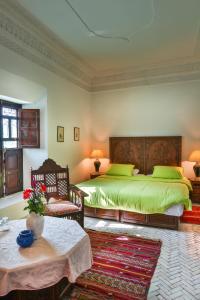 een slaapkamer met 2 bedden met groene lakens en een tafel bij Riad Dar El Assafir in Marrakesh