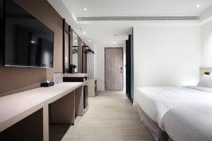 a hotel room with a bed and a tv at KEEBE Hotel in Keelung