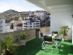 balcón con mesa, sillas y ciudad en Yourpenthouseinmadeira en Funchal