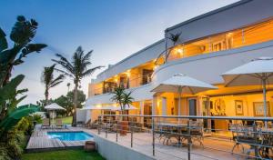 a building with a pool and tables and umbrellas at Vetho House in Ballito