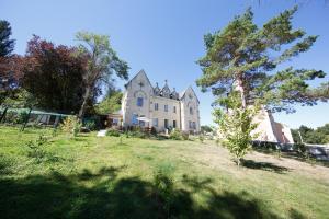 une grande maison blanche avec un arbre dans la cour dans l'établissement Le manoir de Sanilhac, à Notre-Dame-de-Sanilhac