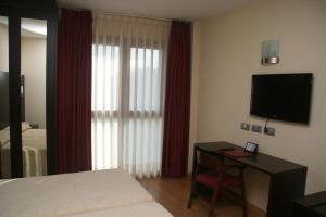 a hotel room with a bed and a desk with a television at Hotel 44 in Gijón
