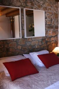 ラストレスにあるCasa rural La Casona del Piqueroの赤い枕2つと鏡2つ付きのベッド1台