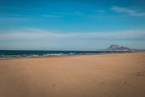 a beach with a mountain in the distance and the ocean at Casa a 50 metros del Mar in Oliva