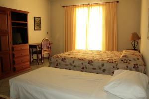 a bedroom with two beds and a desk and a window at Hotel Fazenda Bela Vista in César de Pina