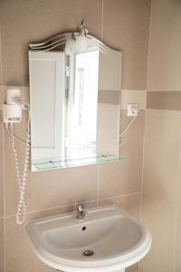 W łazience znajduje się umywalka z lustrem i okno. w obiekcie Apartments O Sole Mio w mieście Vukovar