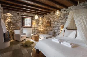 ein Schlafzimmer mit einem Bett und einer Steinmauer in der Unterkunft Adis Oneirou in Mouresi