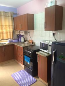 a kitchen with wooden cabinets and a black stove at Pumzika Place in Nairobi