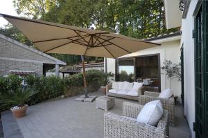 un patio con ombrellone, sedie e divano di Villa Manziana a Manziana