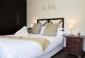 a bedroom with a white bed and a wooden nightstand at Keren's Vine Guesthouse in Stellenbosch