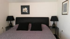 1 dormitorio con 1 cama con almohadas negras y 2 lámparas en G&B Apartments, en Trogir