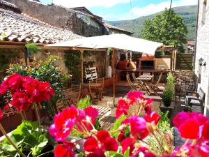 un patio con flores rojas y una sombrilla en Apartamentos San Antonio de Garabandal, en San Sebastián de Garabandal