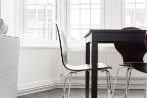 a black table and chairs in a room with windows at Kennington Apartment A/Apartment in London