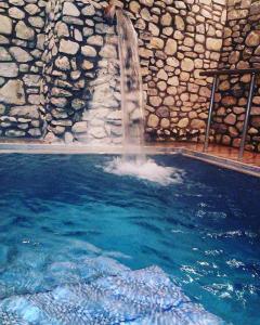 una piscina con cascata di fronte a un muro di pietra di Neraides a Kato Loutraki