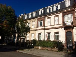 un grand bâtiment blanc avec une clôture devant lui dans l'établissement Villa Schiller, 2 studios côté jardin - quartier Orangerie, à Strasbourg