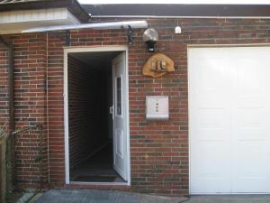 a brick building with a white door and a white garage at Ferienwohnung Haus Antje in Norden