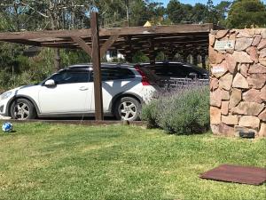 un coche blanco aparcado bajo una pérgola de madera en Esteños de la Pedrera Posada y Spa, en La Pedrera