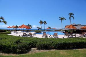 una piscina con sillas y sombrillas y el océano en Condominios Ballena, en Cabo San Lucas
