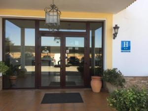 uma entrada para uma casa com uma porta de vidro em Hotel El Capricho em Villanueva del Trabuco