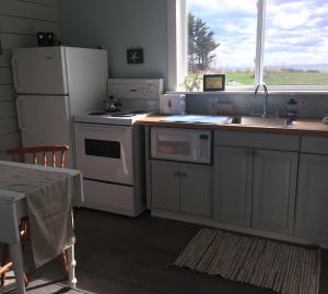 cocina con electrodomésticos blancos, fregadero y ventana en BlueFin Cottage, en Indian Harbour