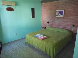 a bedroom with a bed with a green comforter at Hosteria Nido de Condores in Mina Clavero
