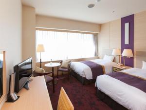 a hotel room with two beds and a flat screen tv at Chofu Creston Hotel in Chofu