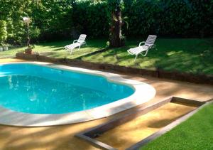 einen Pool mit zwei Gartenstühlen und zwei Stühlen in der Unterkunft Hosteria del Sur in Villa Gesell