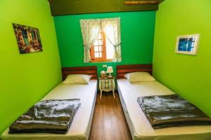 2 letti in una camera con pareti verdi di Just Coffee Hostel 2 a Beigan