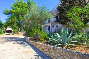 a house with a stone retaining wall next to a street at Apartments Vlatko in Krk
