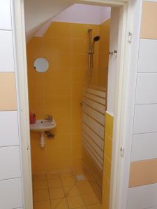 a yellow bathroom with a sink and a shower at Apartmany u Dvora in Jihlava