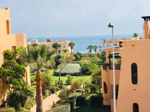 カサーレスにあるEstepona - Casares Beach Golf Apartmentsのヤシの木と海の景色を望むリゾートです。