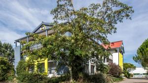 un edificio con un árbol delante de él en B&B HOTEL Agen en Agen