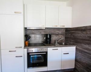 una cucina con armadi bianchi, piano cottura e lavandino di Vogelsand 323 a Cuxhaven