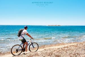 a man riding a bike on top of a beach at Approdo Resort Thalasso Spa in Castellabate