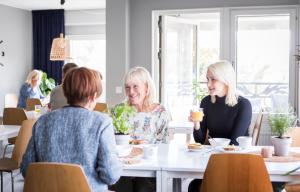 Duas mulheres sentadas à mesa a comer comida. em Linnéplatsens Hotell & Vandrarhem em Gotemburgo