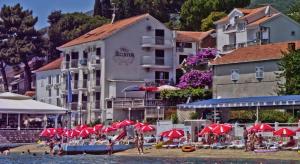 a group of red umbrellas on a beach next to a building at Apartmani Kalinic in Bijela