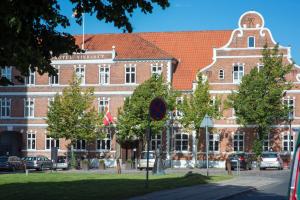 um grande edifício de tijolos com carros estacionados em frente em Hotel Vinhuset em Næstved