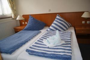 uma cama com almofadas listradas azuis e brancas e um barco nela em Gästehaus Restaurant Norddeich em Norddeich