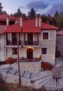 uma grande casa de pedra com um telhado vermelho em Thea Valtessinikou em Valtessiniko