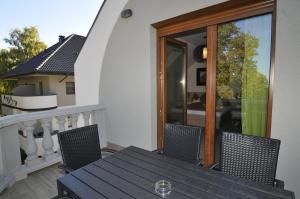 a wooden table and chairs on a balcony with a window at Hotel Corso in Siófok