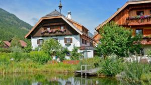 una casa vicino a un lago di fronte a una casa di Pension Gruber a Weisspriach