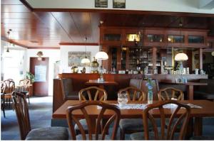 un restaurante con mesas y sillas de madera y un bar en Gästehaus Restaurant Norddeich, en Norddeich