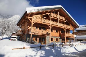 a log cabin in the snow with a car in front at Les Chalets de La Griyotire in Praz-sur-Arly