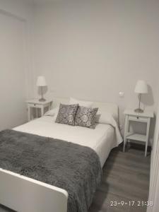 ein weißes Schlafzimmer mit einem Bett mit 2 Tischen in der Unterkunft Piso Vacacional in San Juan de Alicante