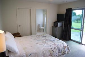 a bedroom with a bed and a sliding glass door at Waihi Beach Getaway-Studio, Ensuite & Private Deck in Waihi Beach